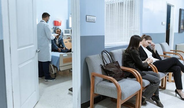 physician and patient in consulting room with patients waiting outside on hospital chairs